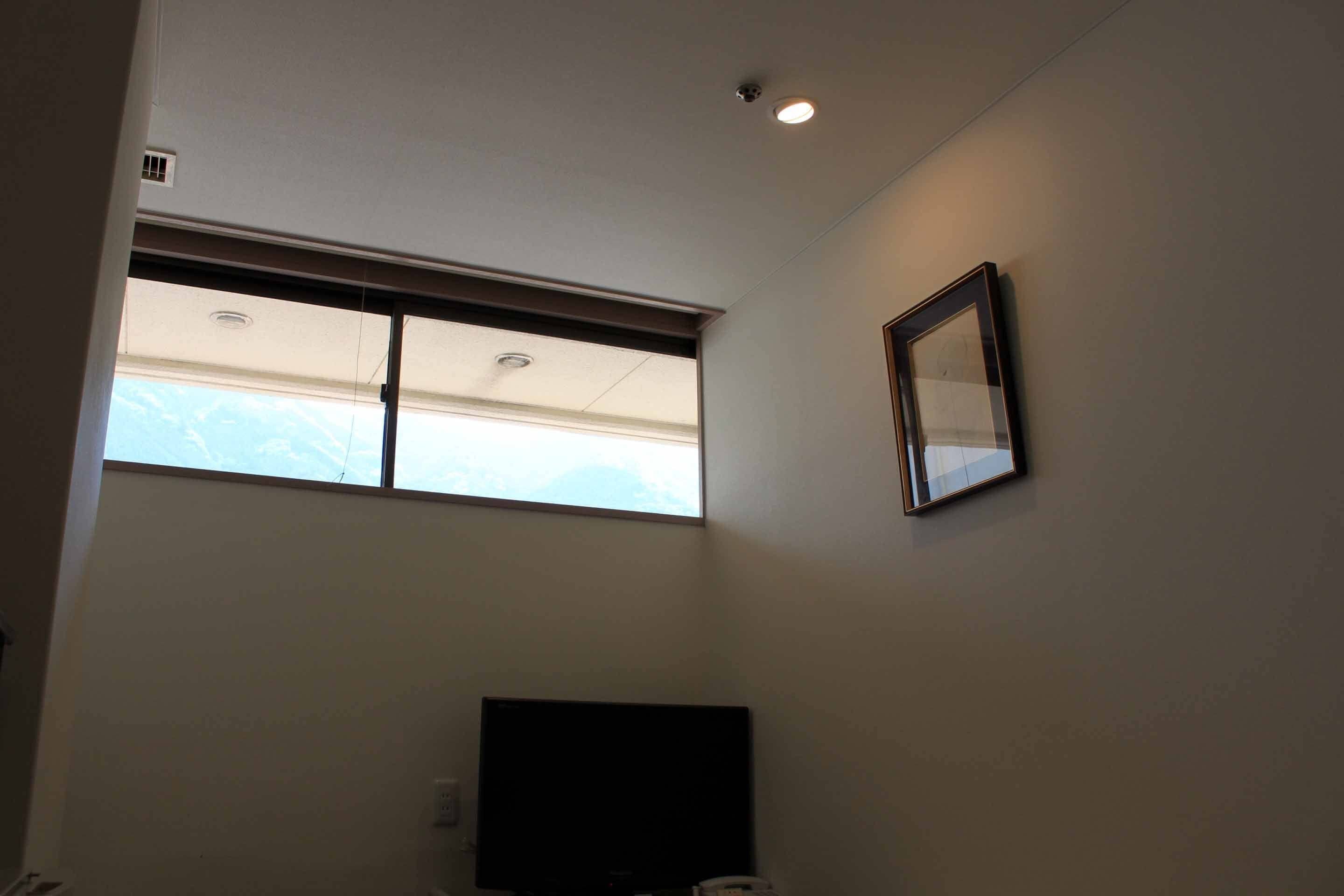 A room with a large window, a flat-screen TV, and a framed picture on the wall.