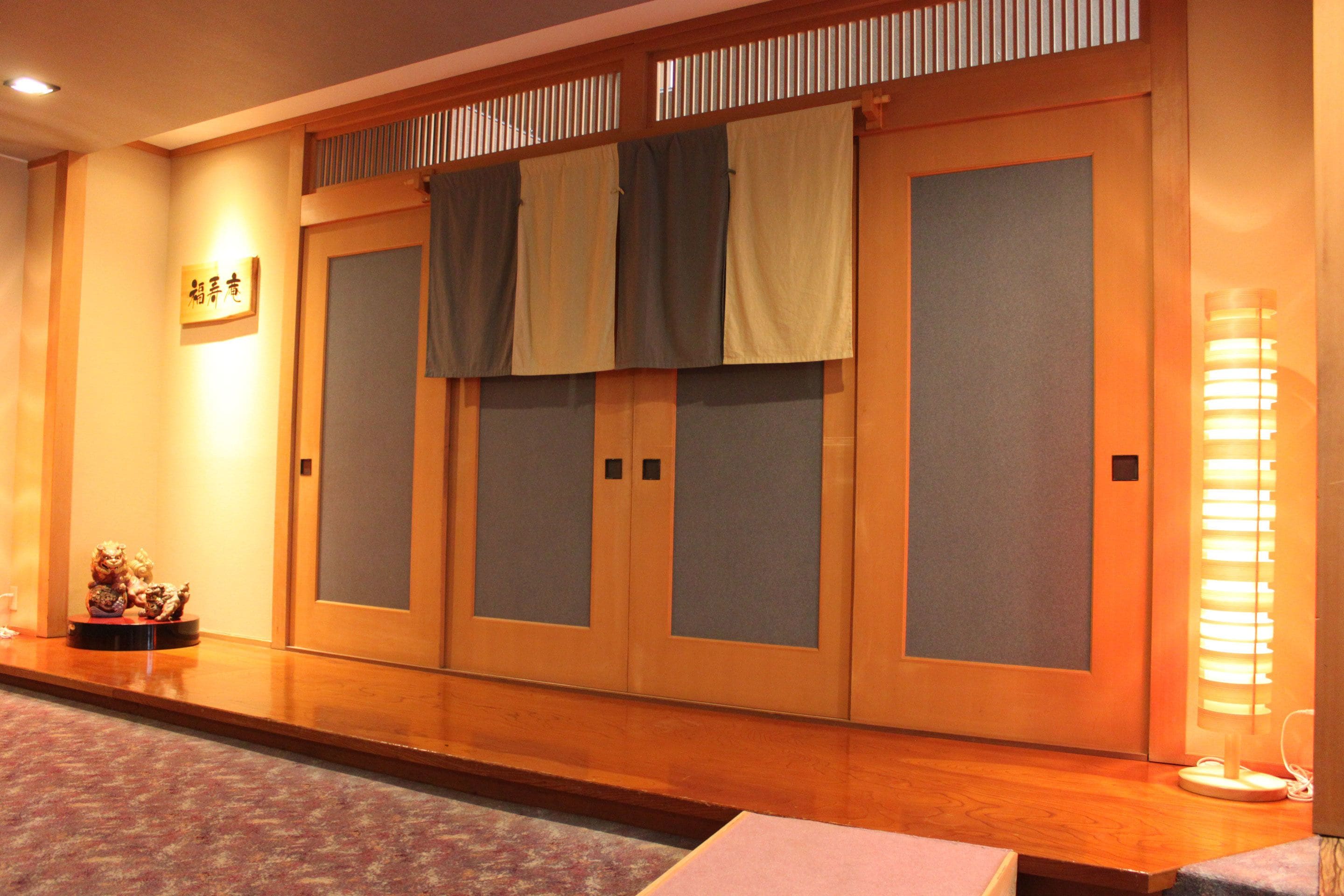 A traditional Japanese room with sliding doors, a wooden floor, and a small statue on a table.