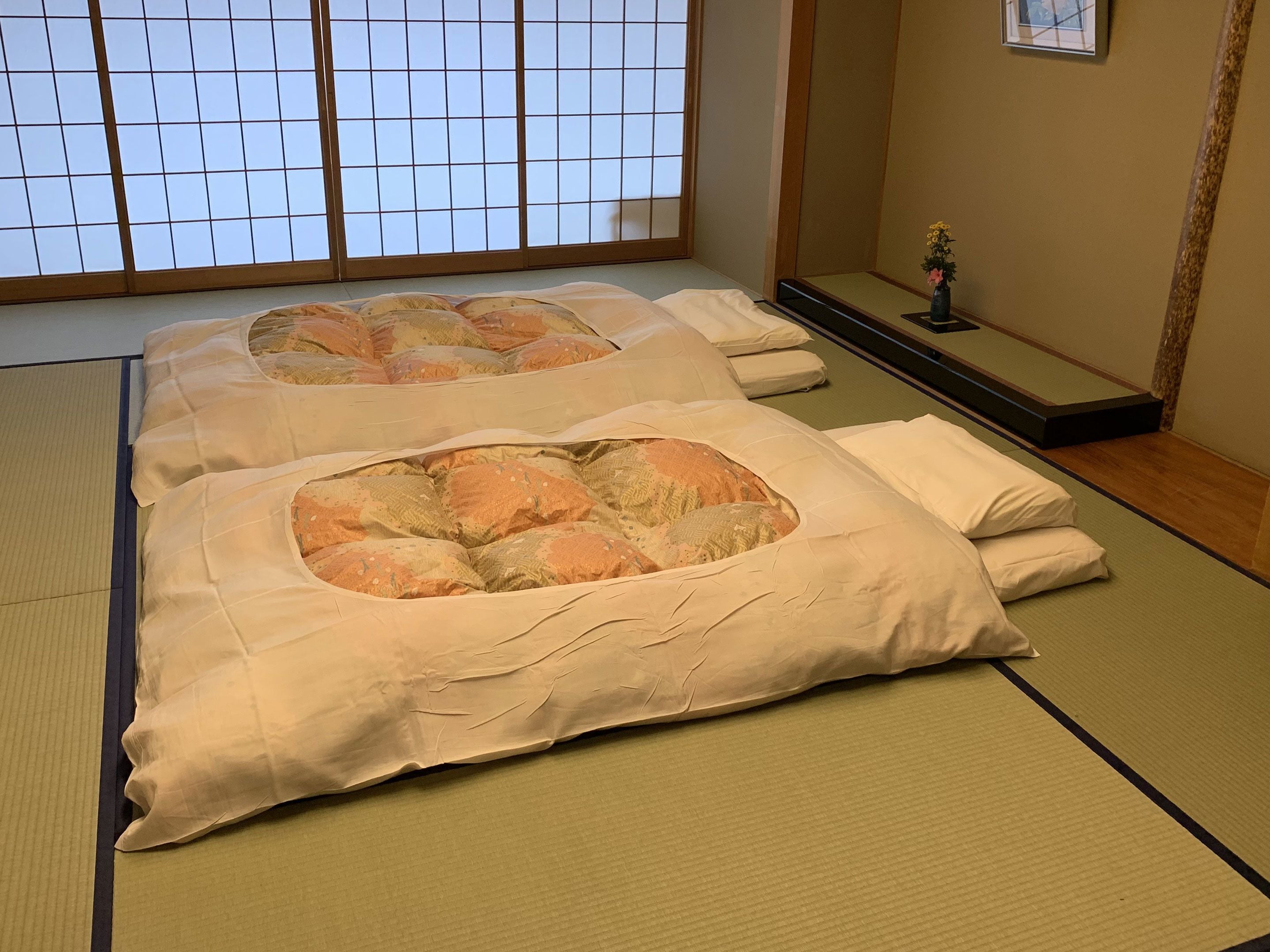 Ein traditioneller japanischer Raum mit Tatami-Matten, Shoji-Schirm und Futon-Bett mit Futon-Matratze.