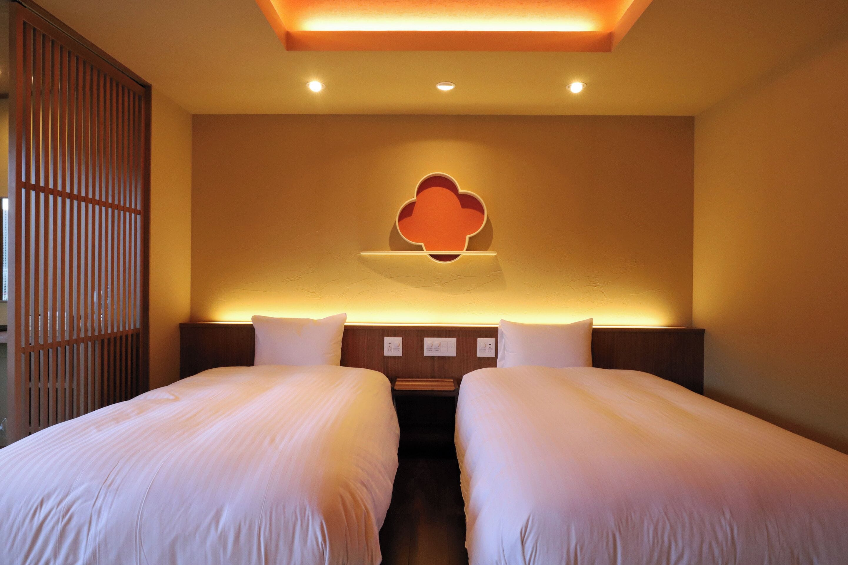 Ein Hotelzimmer mit zwei Betten, einer Holzwand und einer Wandleuchte.