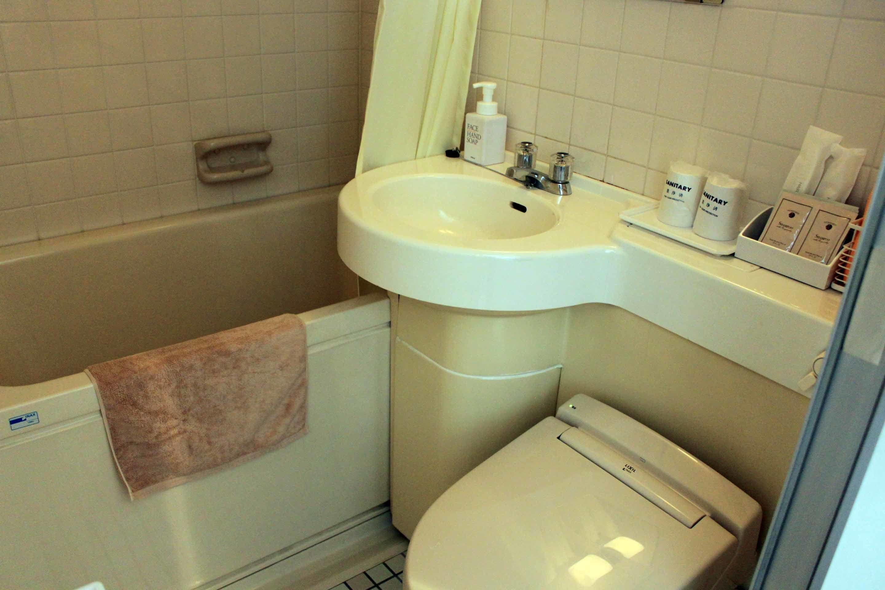 Un baño con lavamanos, espejo e inodoro.