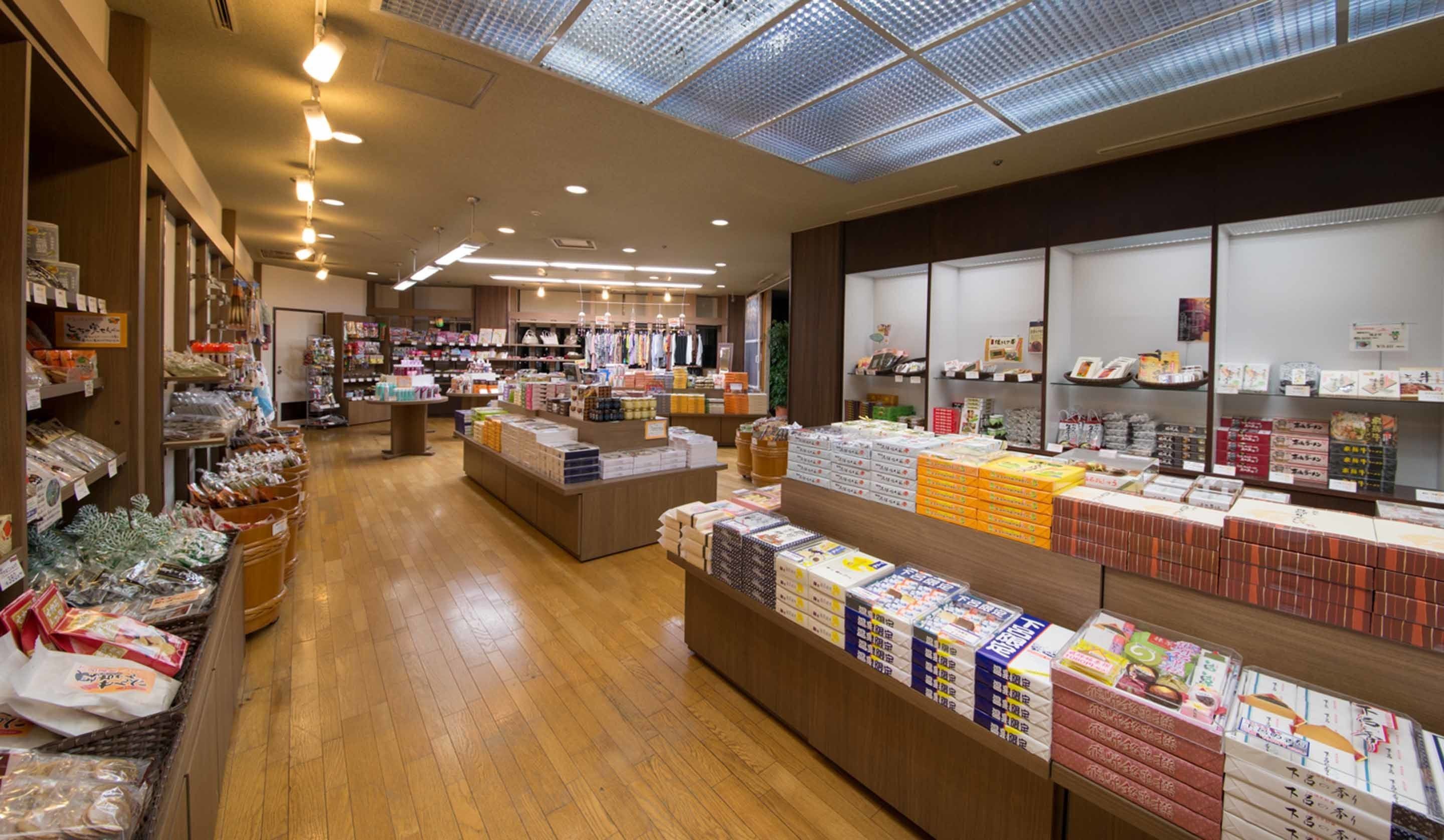 A spacious retail store with wooden flooring and a skylight ceiling. Shelves are stocked with various products, and there are multiple checkout counters.