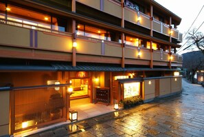 A traditional Japanese ryokan with multiple floors, wooden exterior, and warm lighting. - Kyoto Arashiyama Onsen Ryokan Hanaikada (Kyoto)