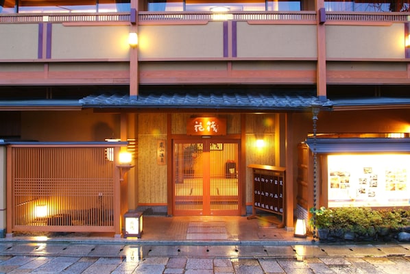 A traditional Japanese building with a wooden entrance, a sign with Japanese characters, and a display board with pictures.