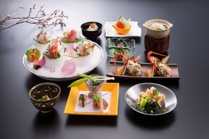Variedad de platillos dispuestos sobre una mesa, incluyendo un plato con un centro de mesa decorativo, un tazón de sopa y varios platos pequeños con diferentes alimentos.