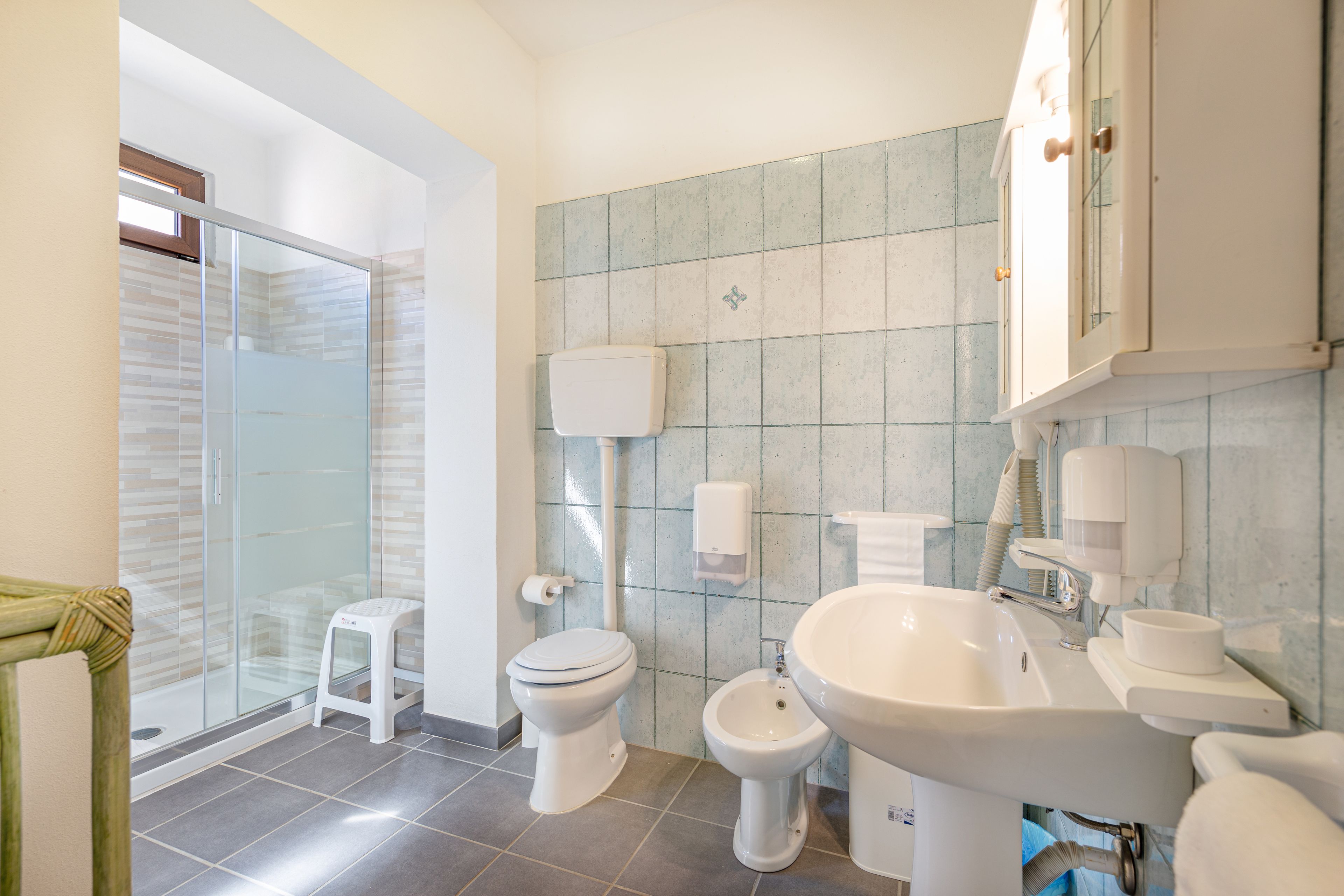 Un baño moderno con cabina de ducha de vidrio, inodoro, bidé y lavamanos.