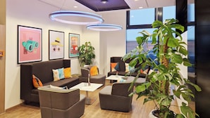 Un espace de détente moderne avec des canapés, une table basse et une grande plante en pot.