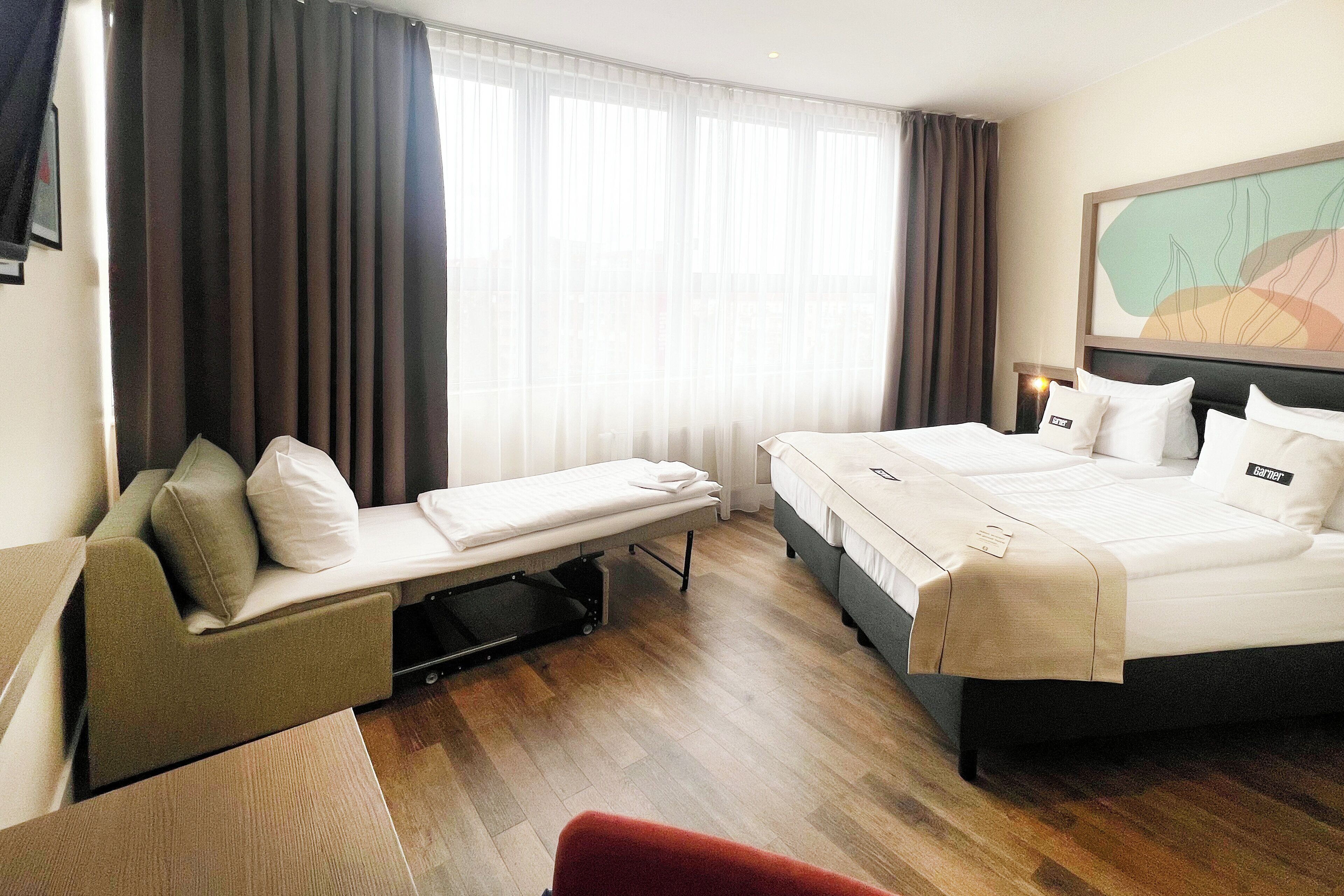 Una habitación de hotel con cama, sofá, escritorio y silla.