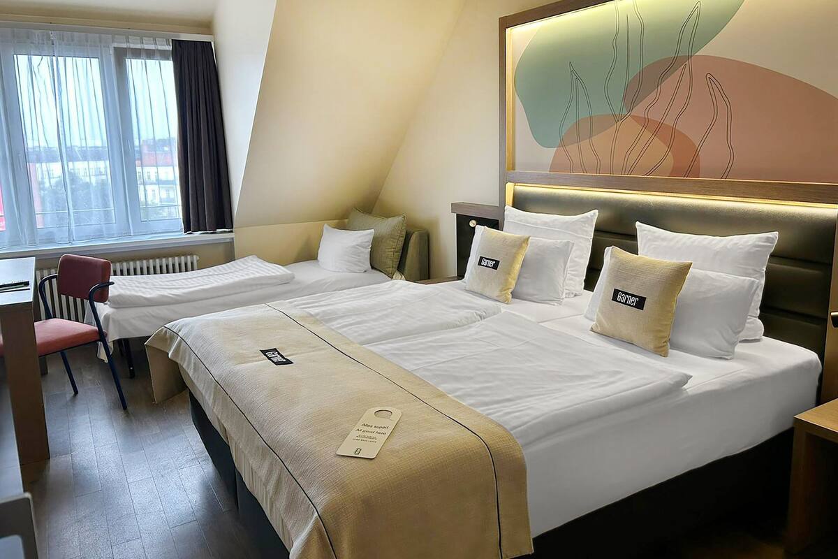 A hotel room with two beds, a desk, and a chair.