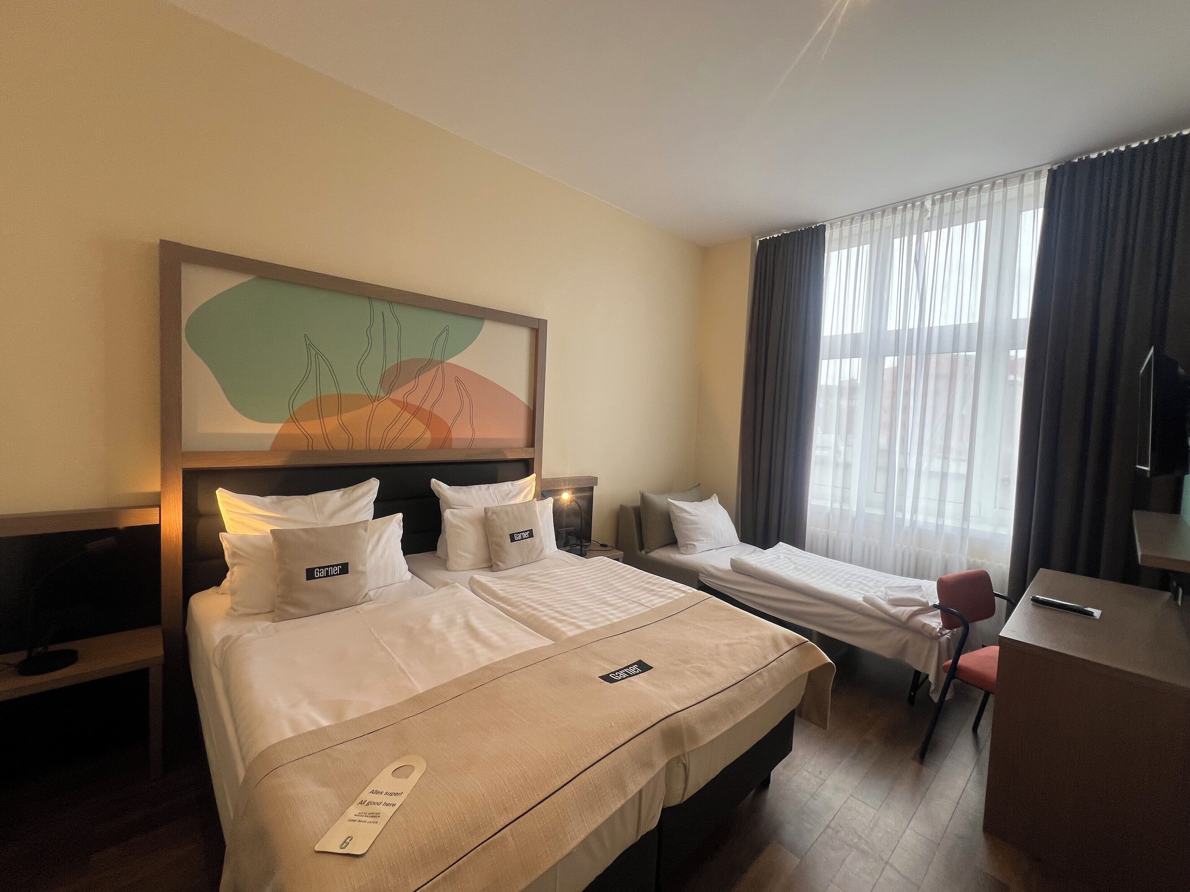 Une chambre d’hôtel avec deux lits, un bureau et une chaise.