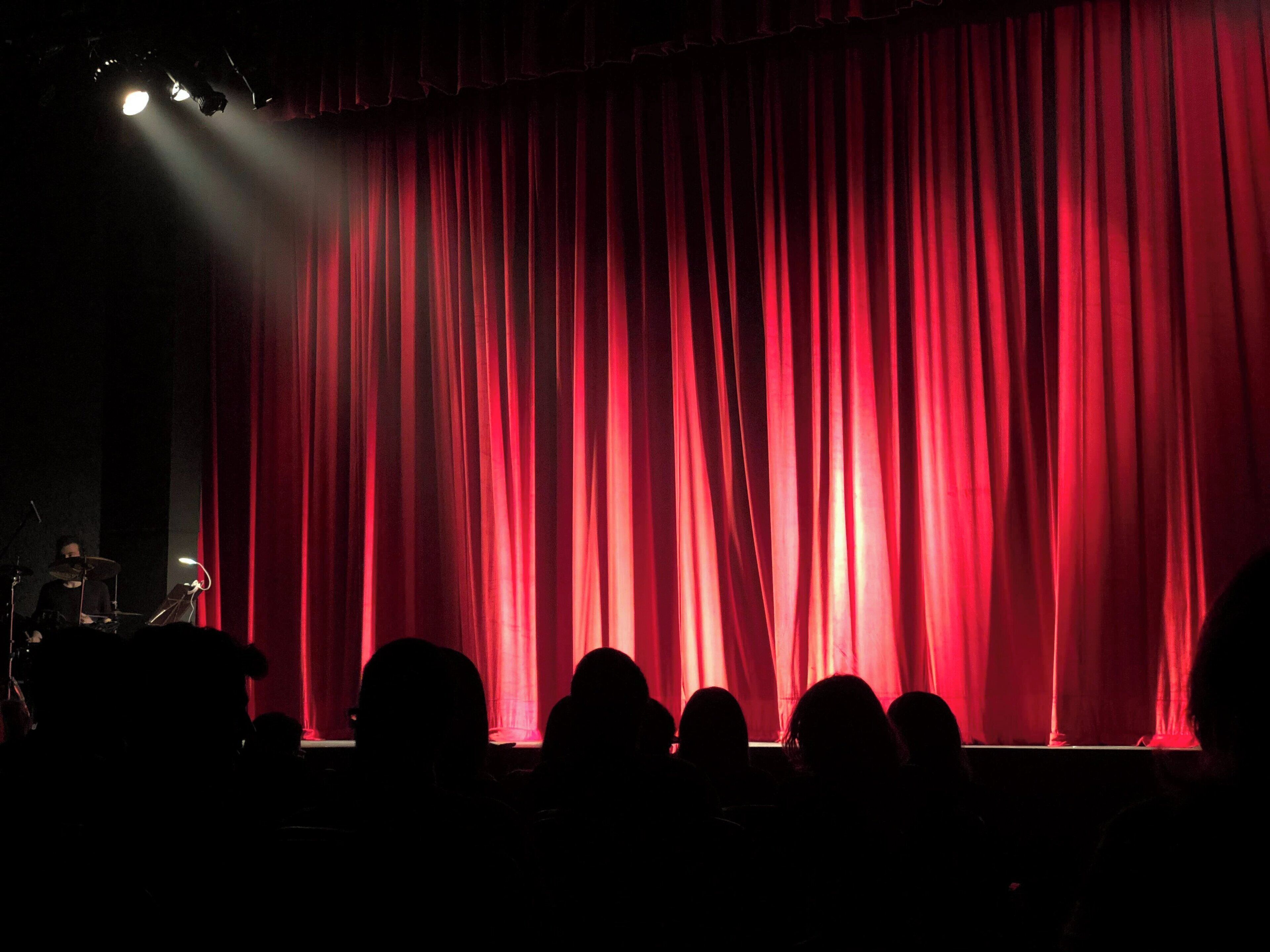 A stage with red curtains and a spotlight.