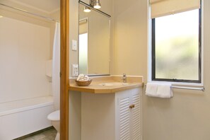A bathroom with a bathtub, toilet, sink, and a window with a view.