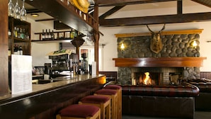 Una zona de bar con taburetes de madera, una chimenea de piedra y una cabeza de animal montada.