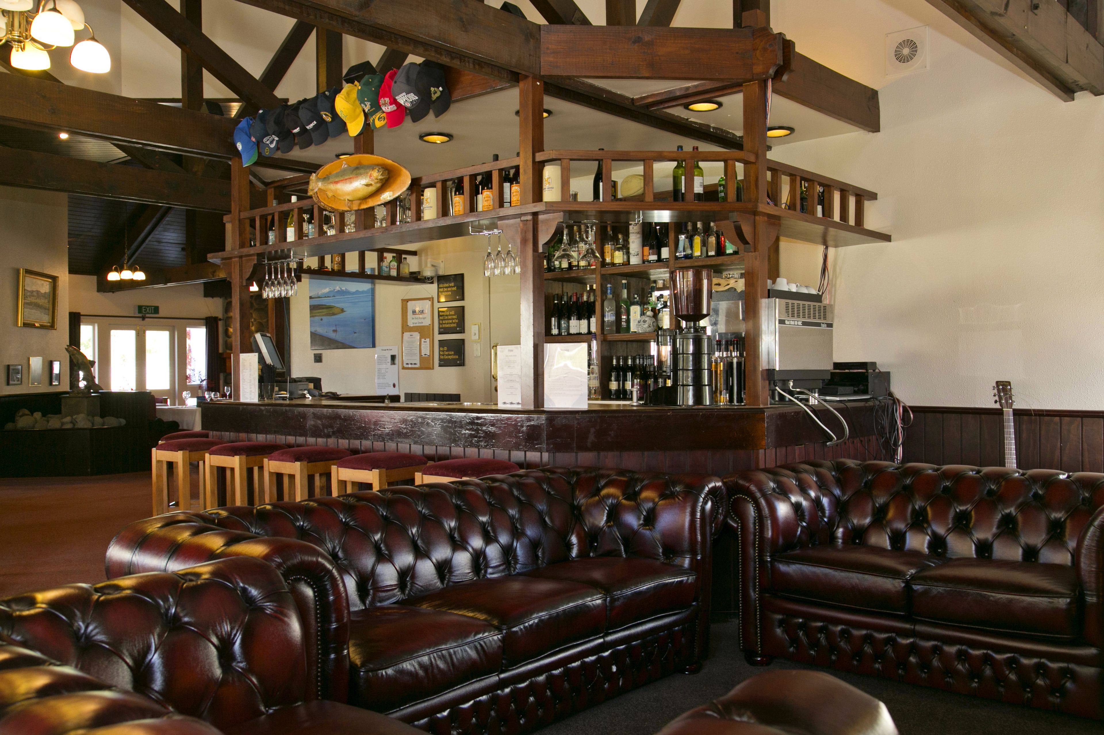 A bar area with leather seating and a variety of bottles and glasses on shelves.