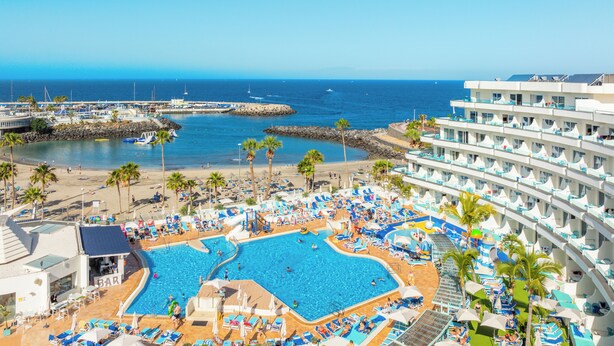 Un resort con un amplio espacio de piscina, varios niveles de balcones y vistas al mar.