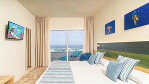 Habitación de hotel con una cama grande, vistas al mar, un televisor y obras de arte en las paredes.