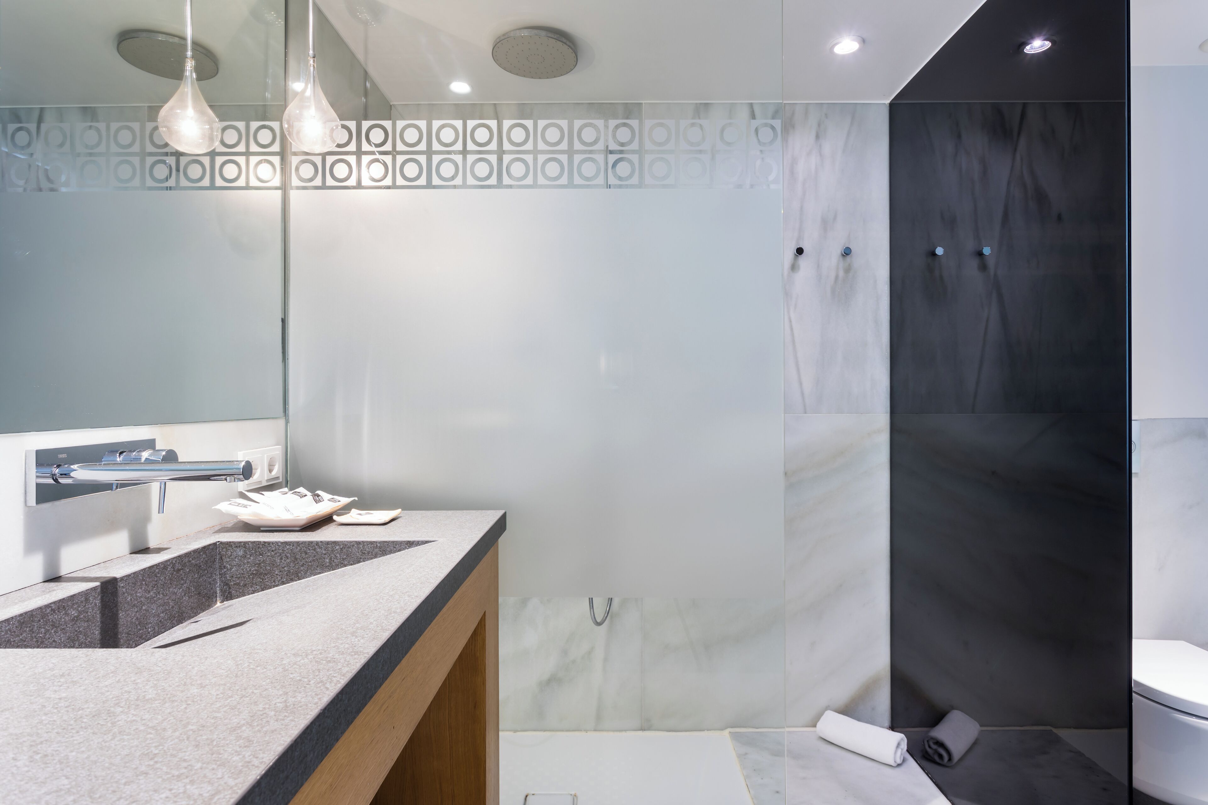 A modern bathroom with a marble vanity, a glass shower enclosure, and a toilet.