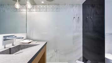 A modern bathroom with a marble vanity, a glass shower enclosure, and a toilet.