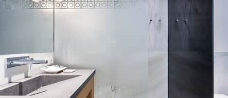 Une salle de bain moderne avec un meuble-lavabo en marbre, une cabine de douche en verre et des toilettes.