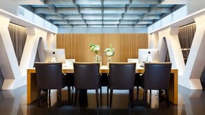 Una sala de conferencias moderna con techo inclinado, paneles de madera y dos iMac de Apple sobre los escritorios.