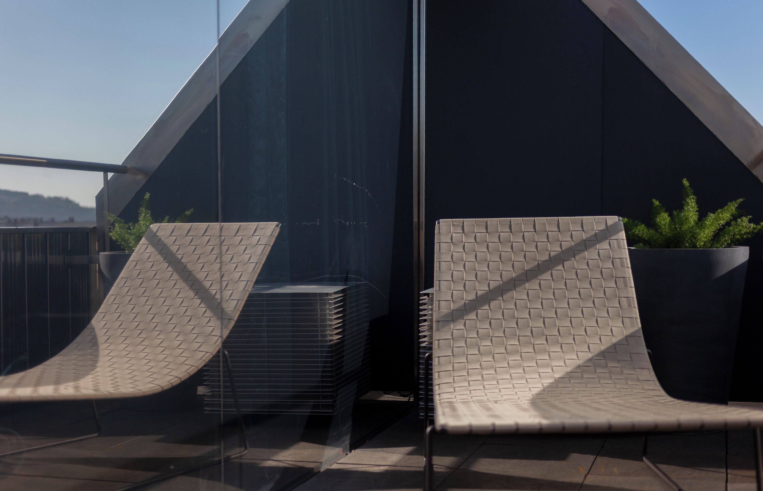 A modern outdoor seating area with two cushioned chairs and a potted plant.