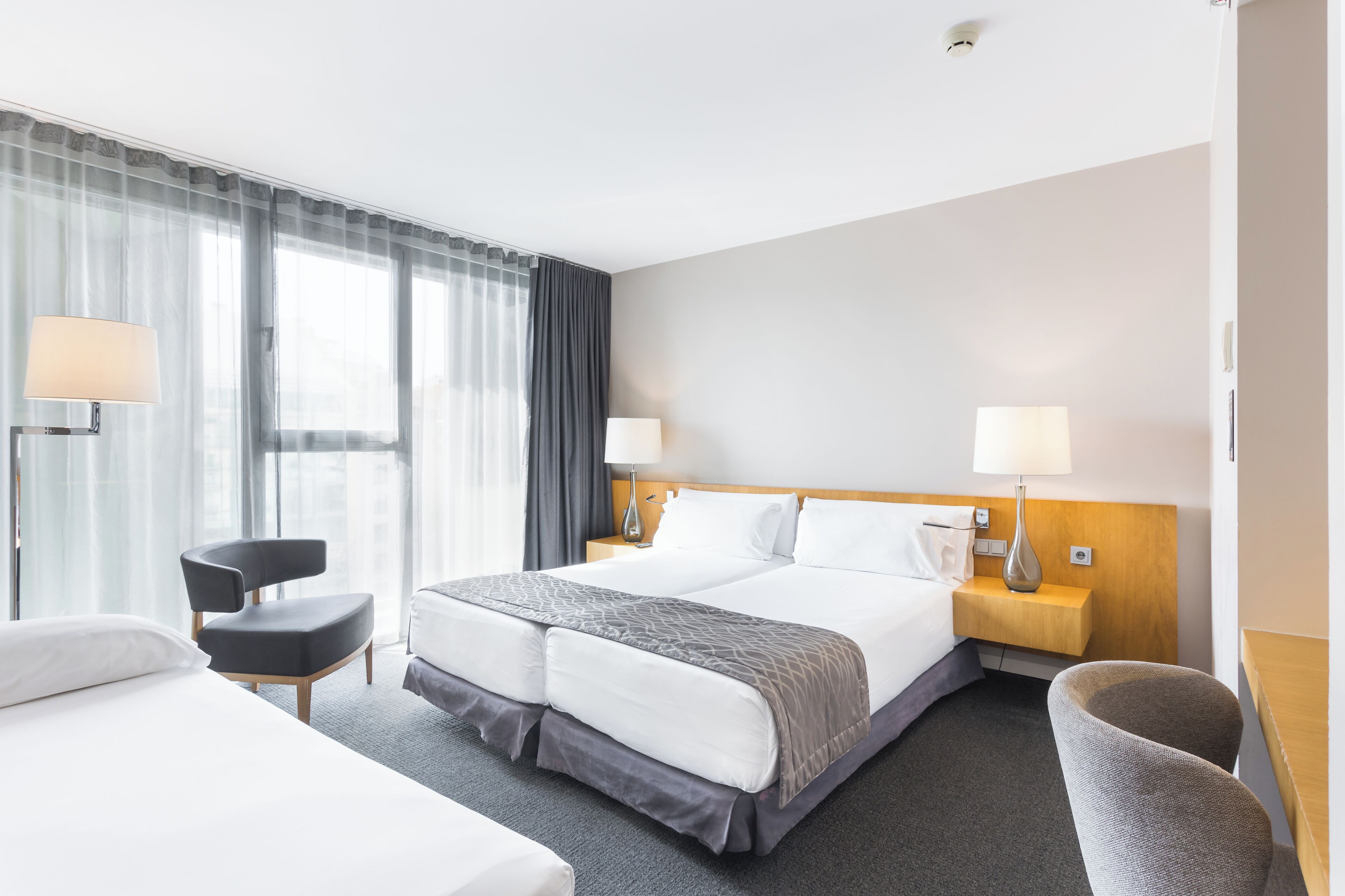 Une chambre d’hôtel avec un grand lit, deux tables de chevet, une chaise et un bureau.
