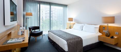 A hotel room with a bed, desk, chair, and two lamps.