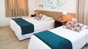 A hotel room with two beds, a wooden headboard, a wall mural, and a window with curtains. - Garibaldi Business Hotel (Porto Alegre)