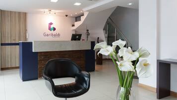 A reception area with a modern desk, a black chair, and a vase with white flowers.