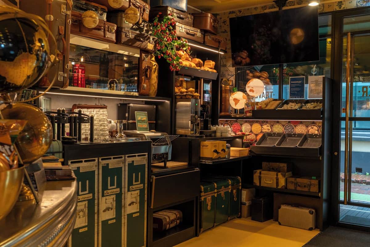 A vintage-themed interior with a coffee machine, vintage suitcases, and a globe display.