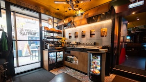 A restaurant interior with a bar area, a cash register, and a refrigerator stocked with beverages. - The Happy Traveler (Groningen)