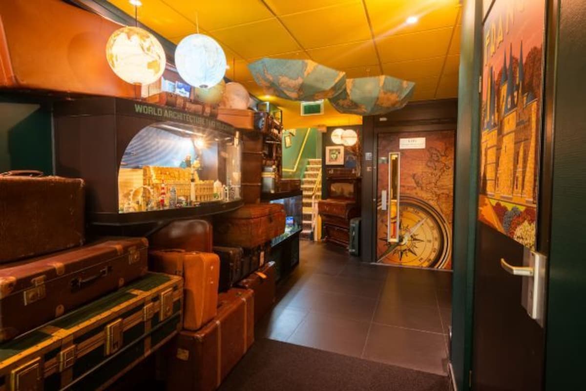 A narrow hallway with vintage suitcases, a globe, and a large clock on the wall.