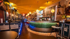 A bar area with a reception desk, bar stools, and a counter with a menu. - The Happy Traveler (Groningen)