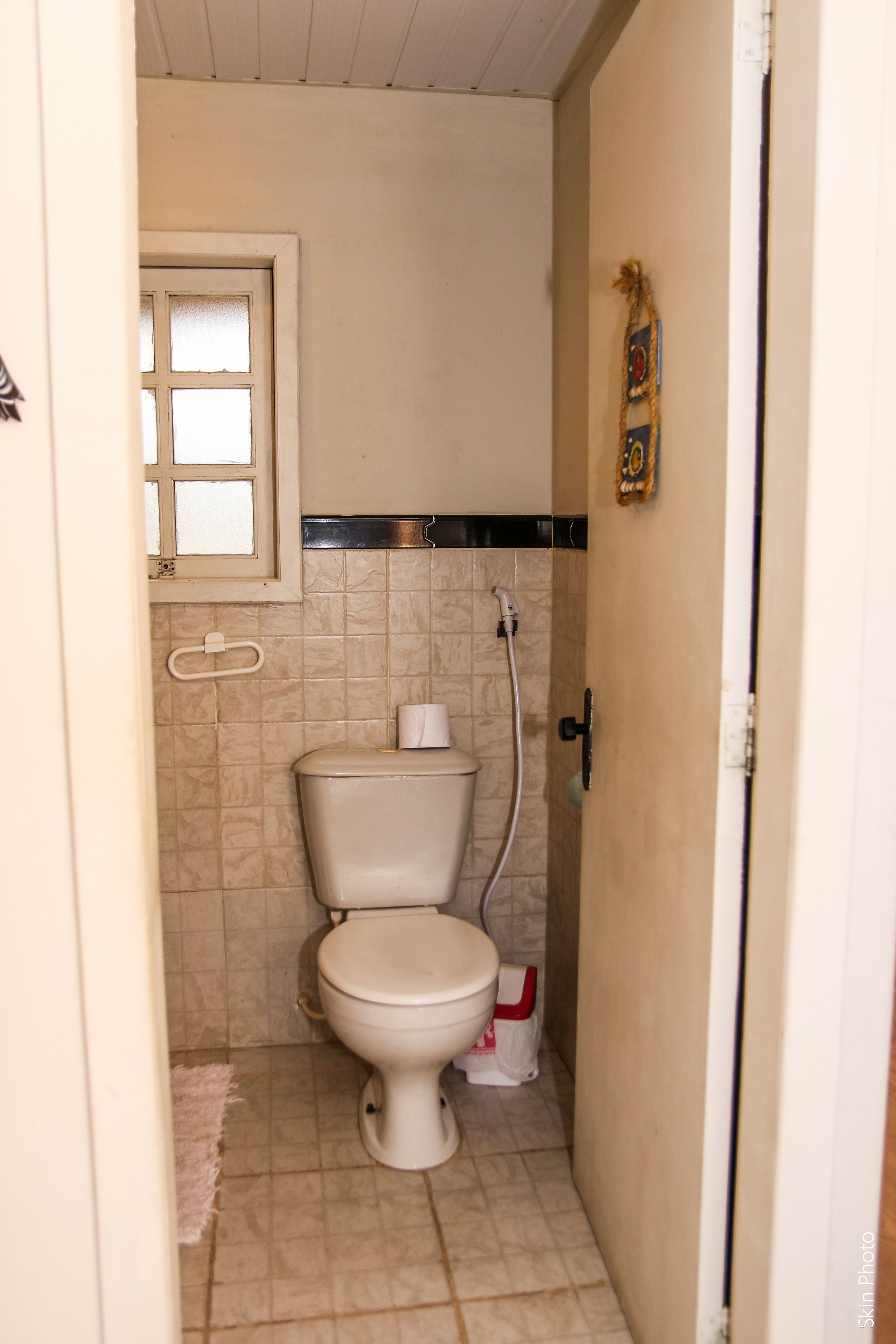 A small bathroom with a toilet, a shower, and a towel rack.