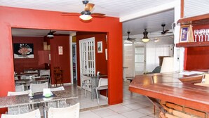 Un coin repas agrémenté d’un mur d’accent rouge, d’un comptoir avec des verres et d’un ventilateur de plafond.