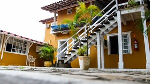 Un bâtiment jaune avec un escalier blanc, un balcon et un extincteur.