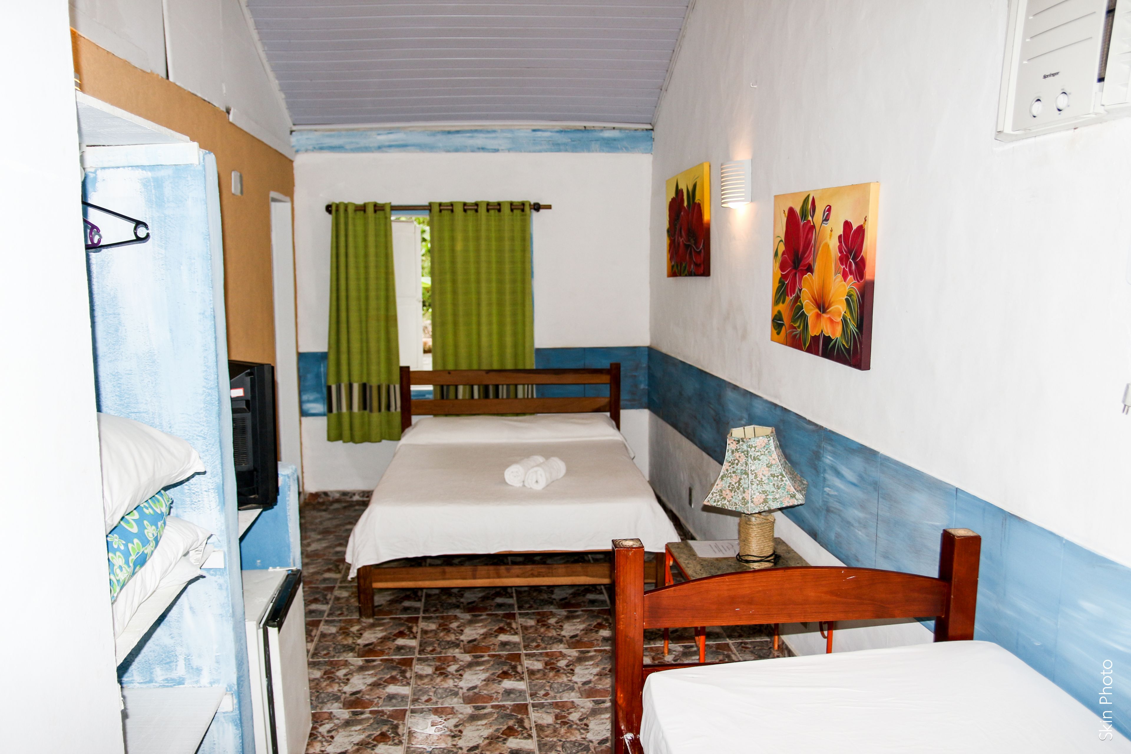 Una habitación pequeña y funcional con dos camas, televisión y una lámpara.
