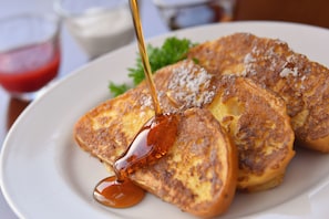 Pain perdu nappé de sirop, servi sur une assiette blanche.