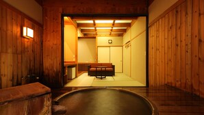 Een traditioneel Japans onsen met een houten interieur, een warmwaterbron en een zithoek met een lage tafel.