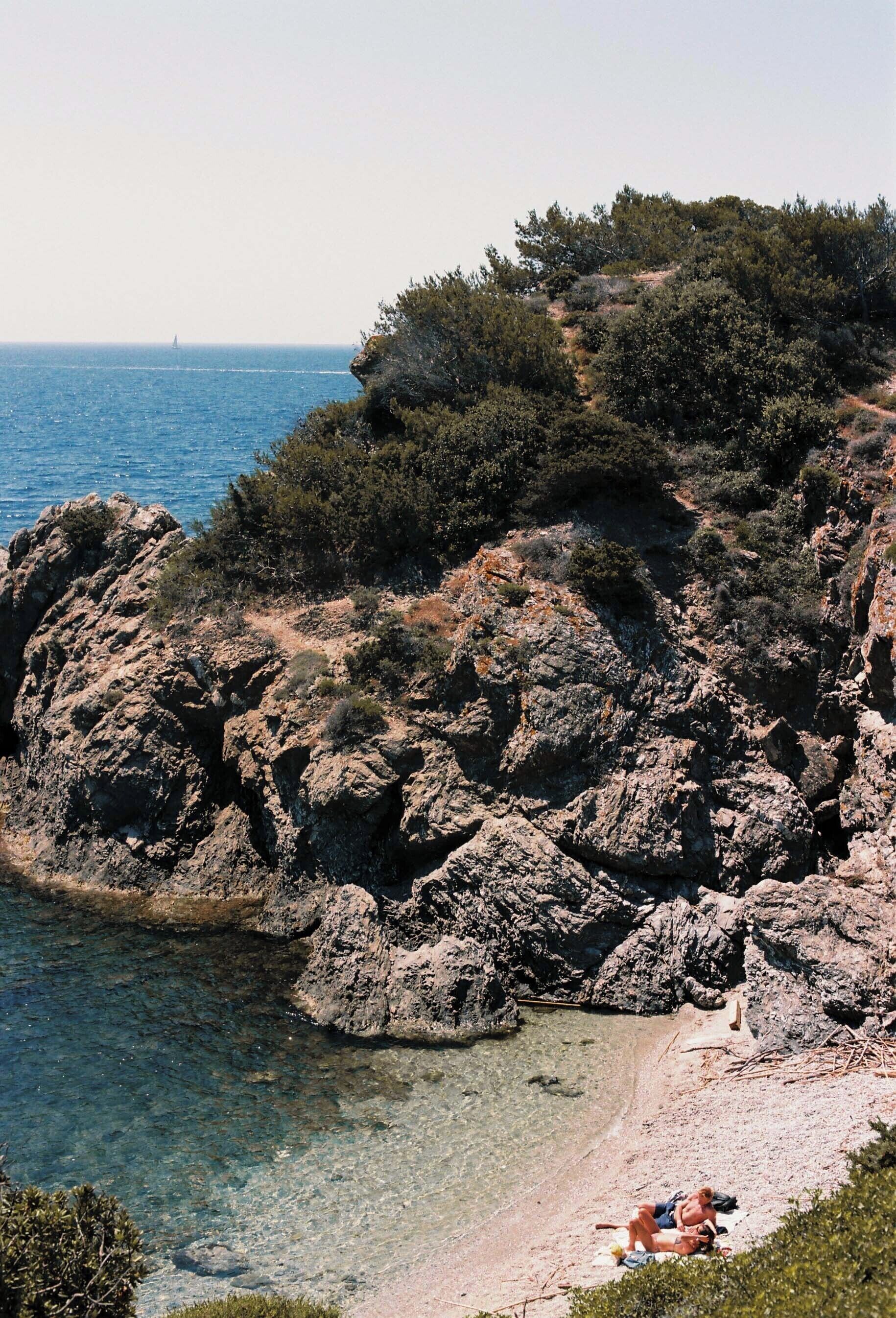 A rocky coastline with clear water and a beach area.