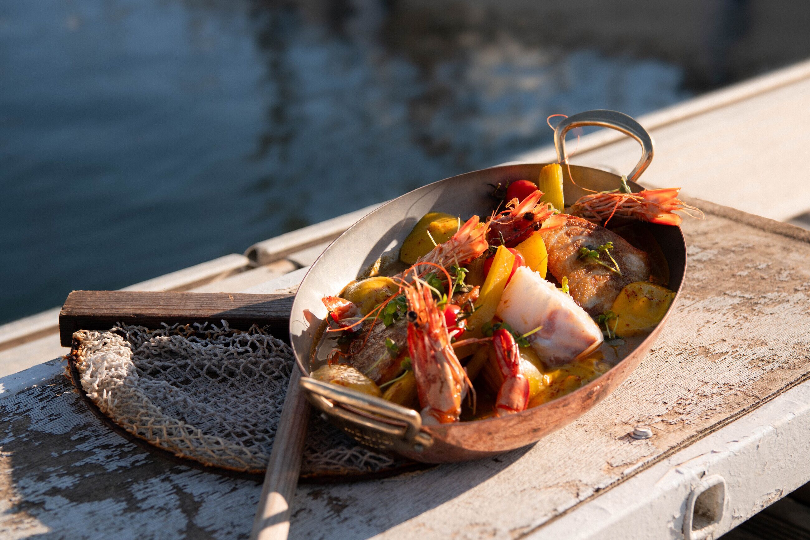 A seafood dish on a boat with a net and a wooden spoon beside it.