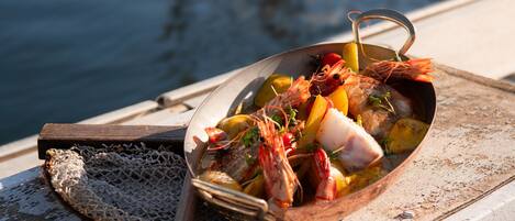 A seafood dish on a boat with a net and a wooden spoon beside it.