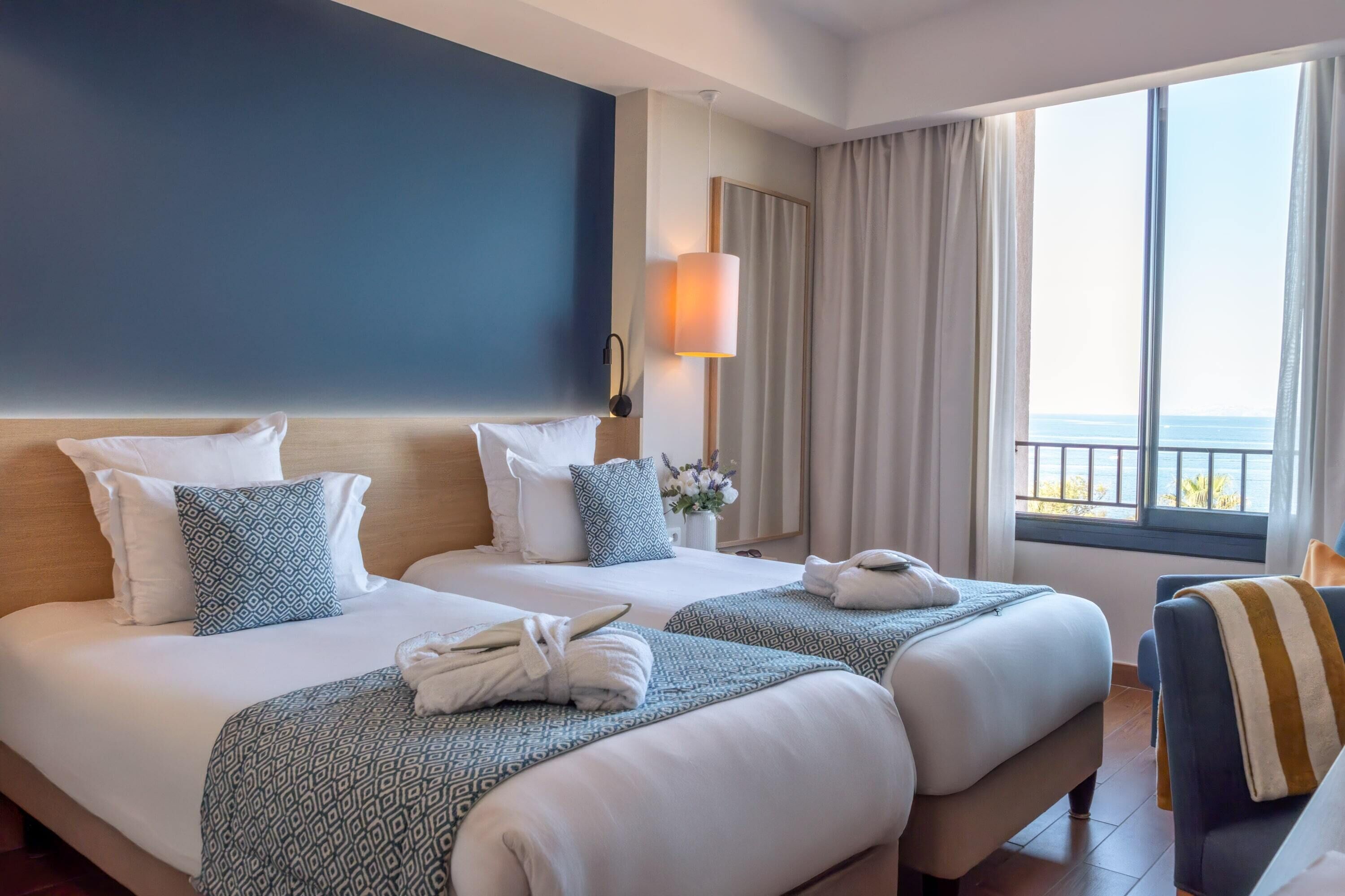 Habitación de hotel con dos camas, un ventanal con vistas y una silla.