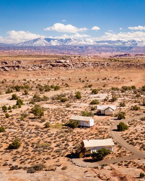 A desert landscape with two tents and a dirt road.