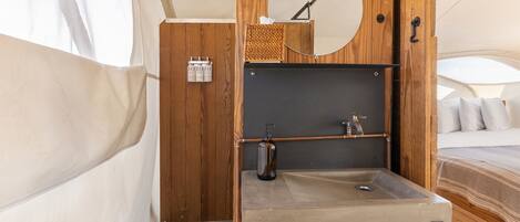 Un baño pequeño con estructura de madera, un lavamanos, un espejo y un perchero para toallas.