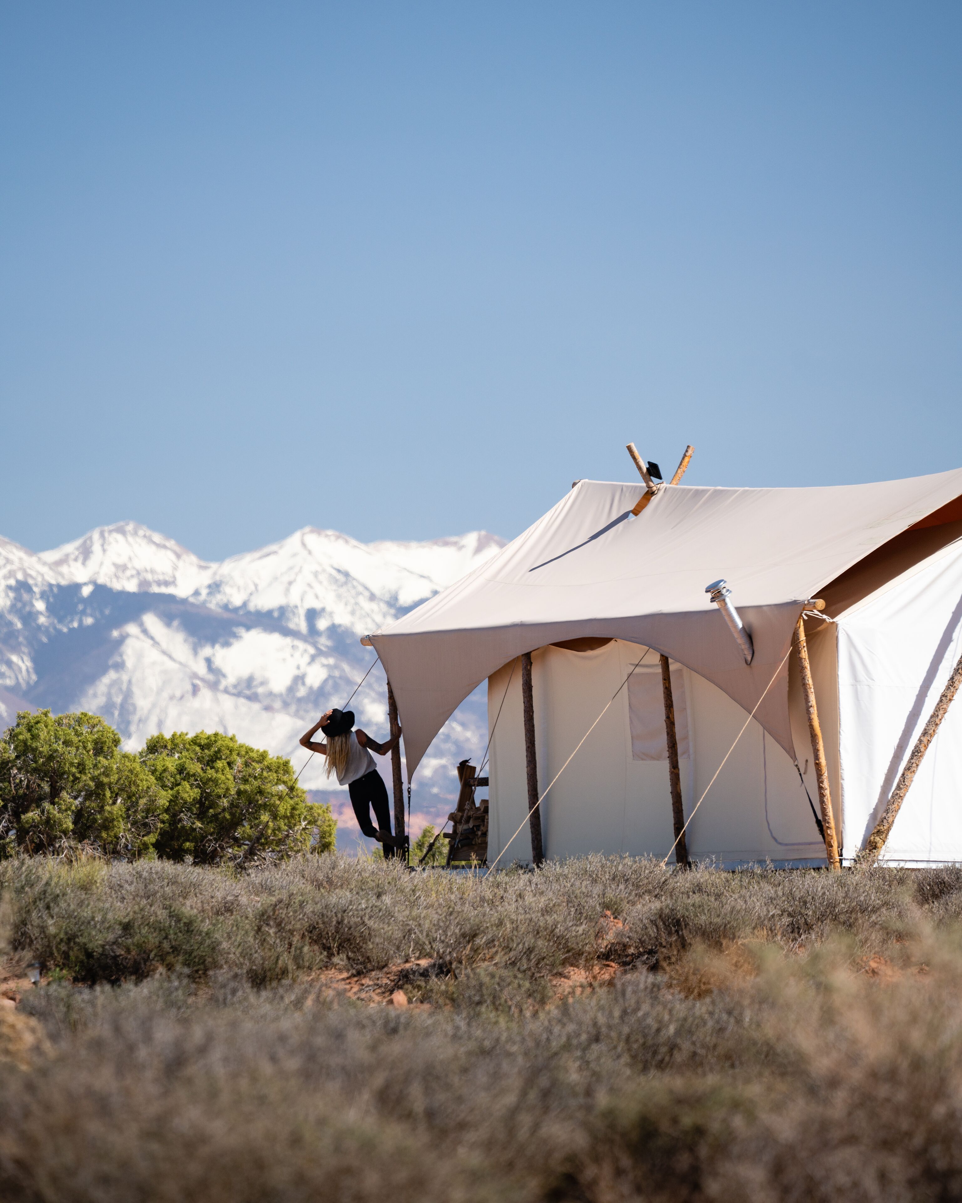 A tent set up in a natural landscape with mountains in the background.