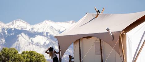 A tent set up in a natural landscape with mountains in the background.
