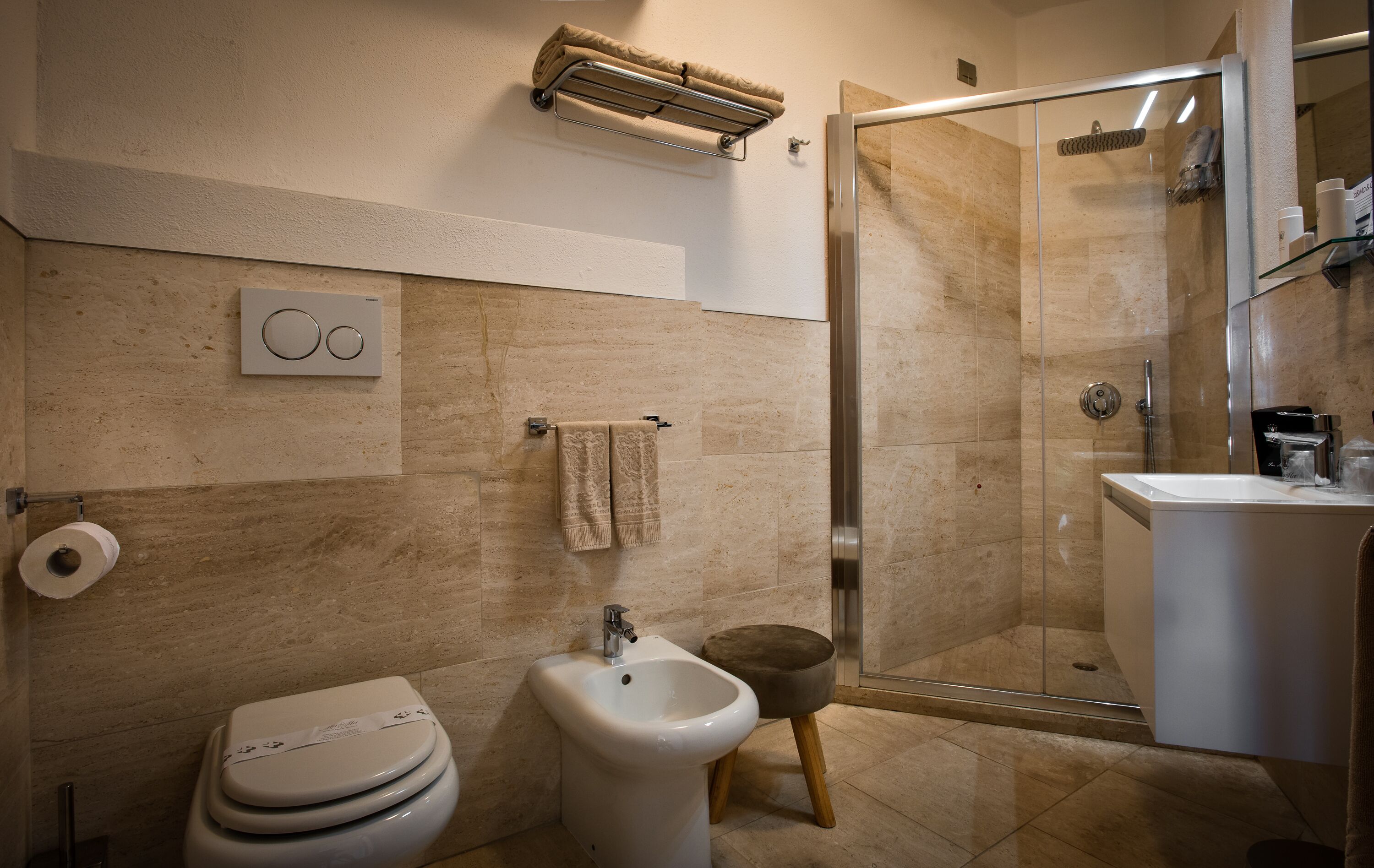Un baño moderno con bidé, inodoro y ducha con cerramiento de vidrio.