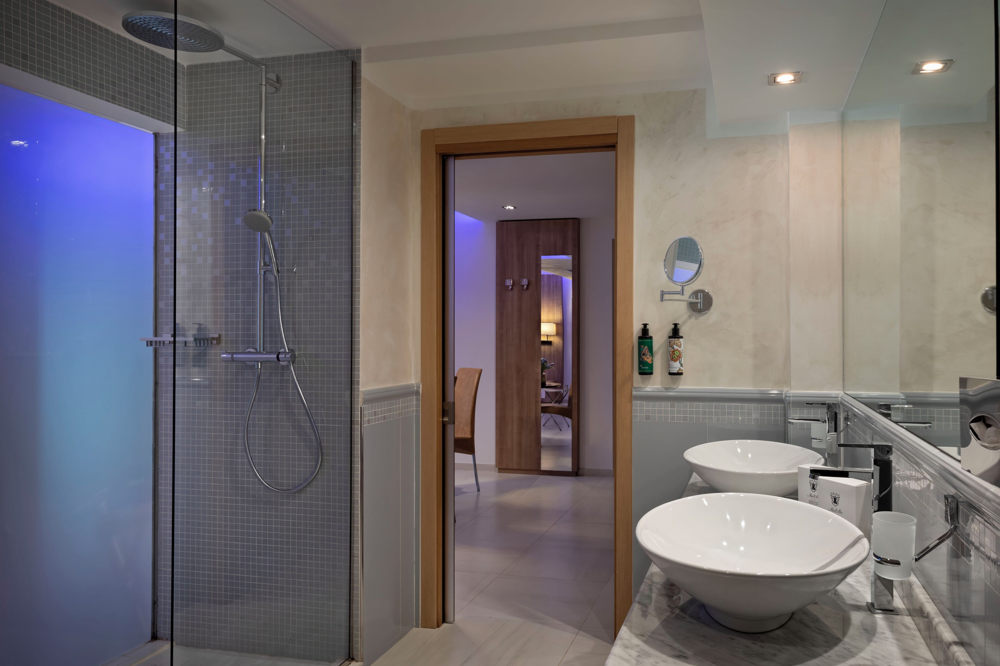 A modern bathroom with a glass-enclosed shower, two sinks, and a mirror.
