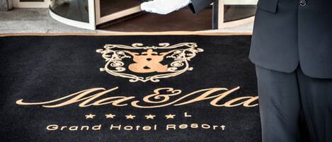 A doormat with the text "Ma & Ma Grand Hotel Resort" and a crown emblem.